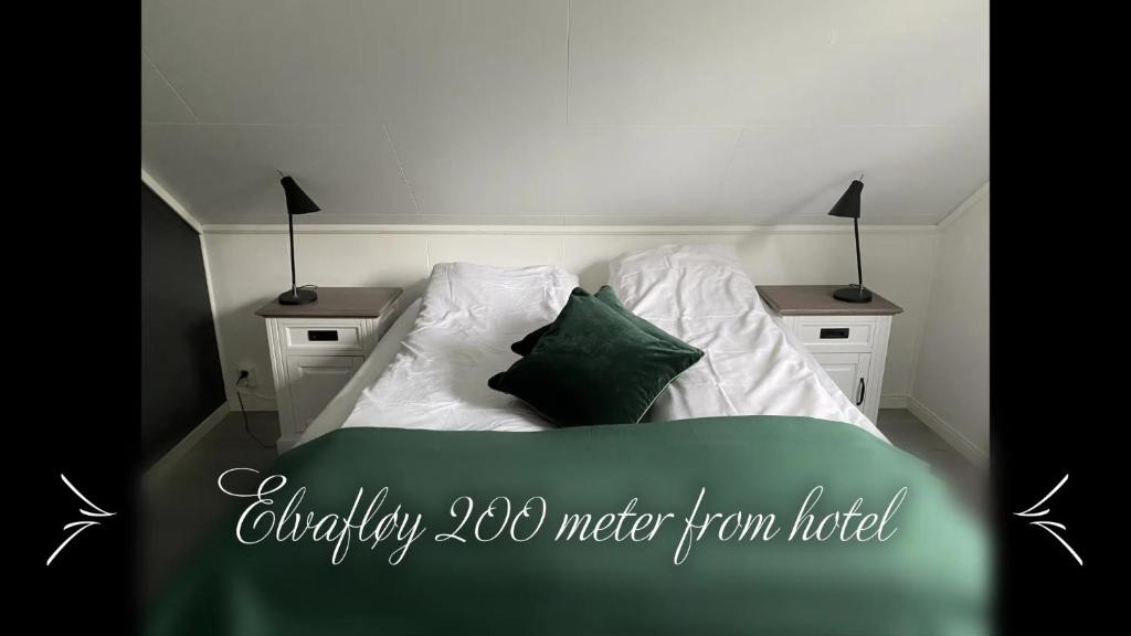 a bed with white sheets and green pillows at Fitjar Fjordhotell in Fitjar