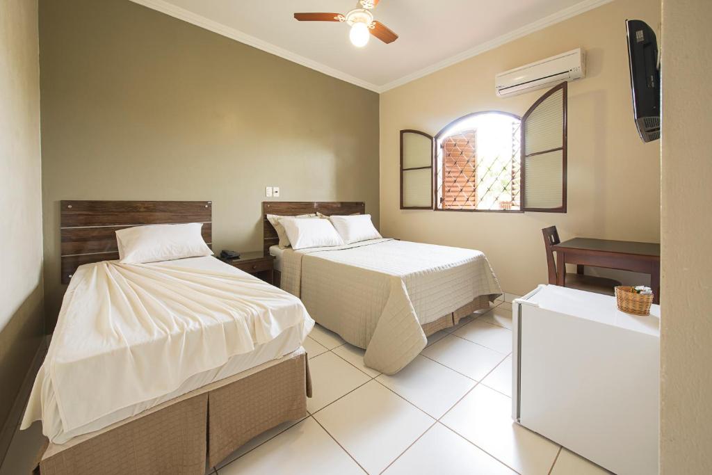 a bedroom with two beds and a tv in it at Hotel Recreio dos Bandeirantes in Sertãozinho