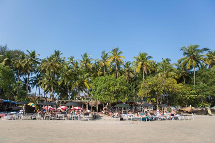a group of people sitting on a beach with umbrellas at Cozy Nook Goa Palolem in Palolem