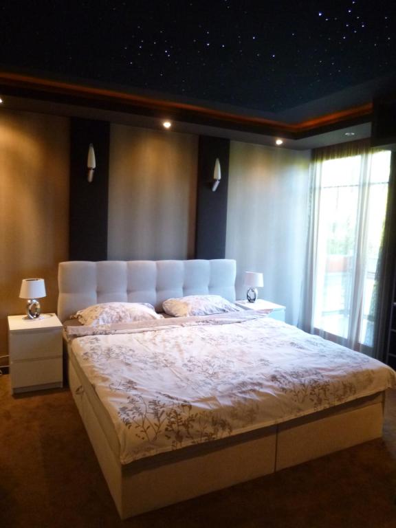 een slaapkamer met een groot bed met een wit hoofdeinde bij Sunny Loft Kecskemét in Kecskemét