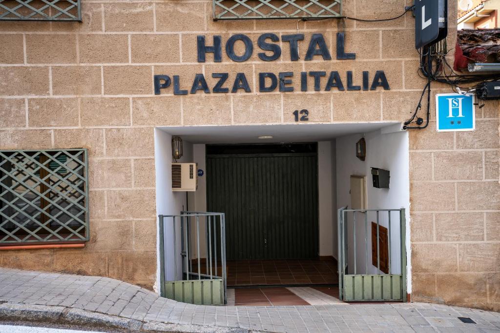 a door leading to a building with a sign on it at Hostal Plaza de Italia in Cáceres