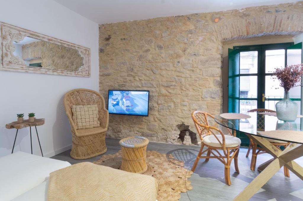 sala de estar con mesa, sillas y pared de piedra en Terra Boutique Apartment, en Girona