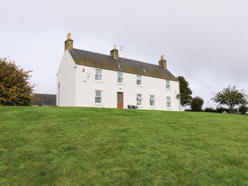 a white house on top of a green field at Todlaw Farm House in Jedburgh