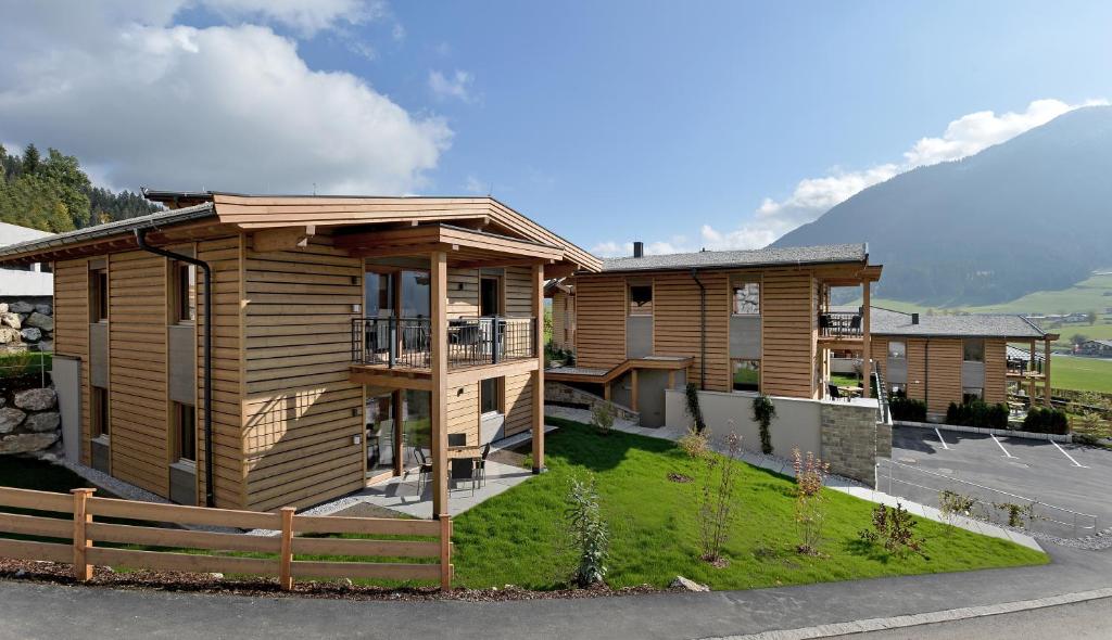 ein Holzhaus mit einem Zaun davor in der Unterkunft Resort Tirol Brixen am Sonnenplateau in Brixen im Thale