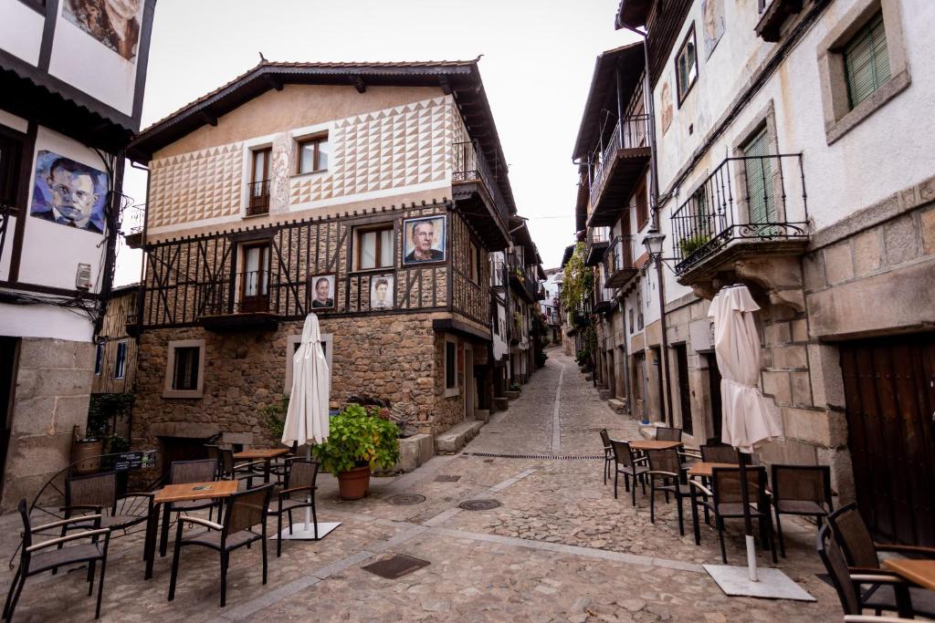 un callejón con mesas y sillas en un edificio antiguo en Los Nidos De Isabel en Mogarraz