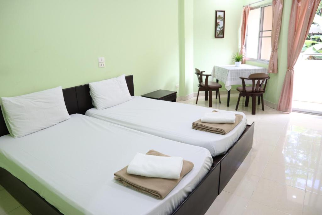 2 Betten in einem Zimmer mit Tisch und Stühlen in der Unterkunft แสนสุขอพาร์ทเมนท์ in Bangsaen