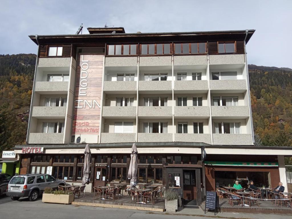 un edificio con mesas y sillas delante de él en Hotel Lodge Inn, en Fiesch