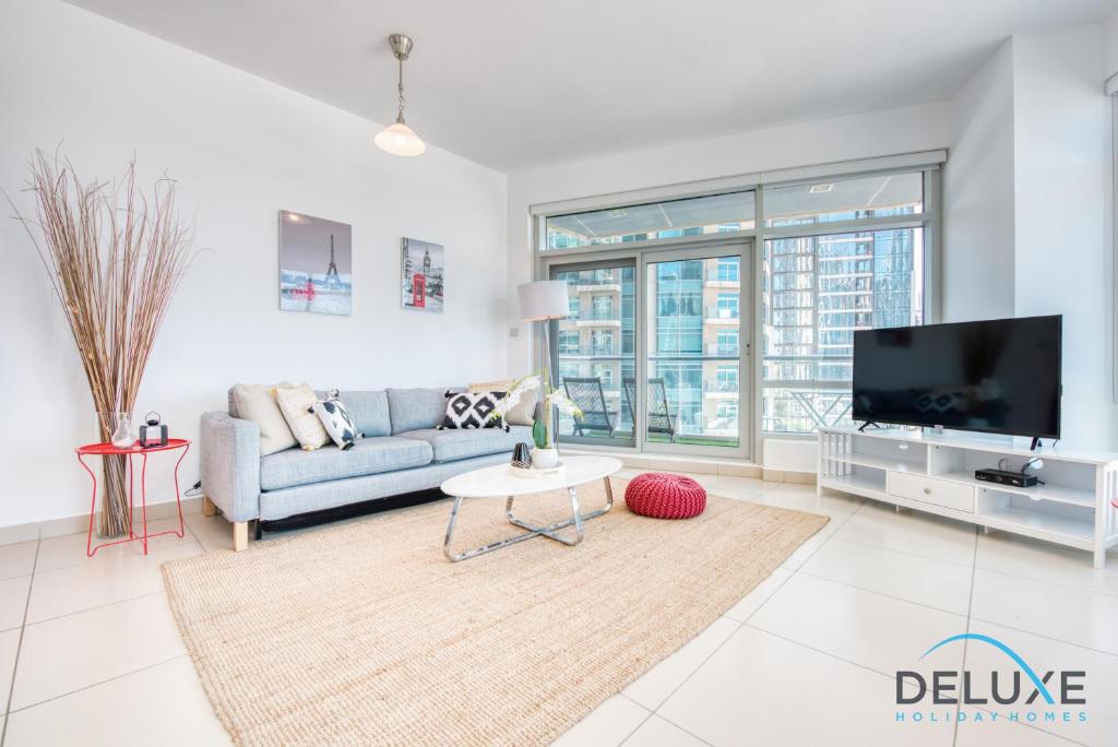 a living room with a couch and a tv at Lively 1BR in Lofts Central, Downtown Dubai by Deluxe Holiday Homes in Dubai