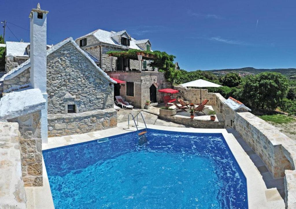 uma piscina em frente a uma casa de pedra em Holiday house Villa Glicinia with hydro-massage pool em Donji Humac