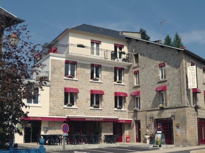 un gran edificio de ladrillo con toldos rojos. en Le Bellerive, en Peyrat-le-Château