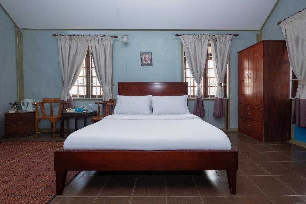 a bedroom with a bed with white sheets and windows at OYO 89873 Nurbayu Chalet in Kuantan