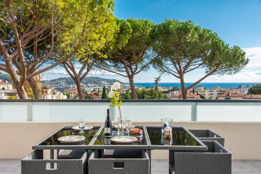 uma mesa com cadeiras e garrafas de vinho numa varanda com árvores em Elegance em Nice