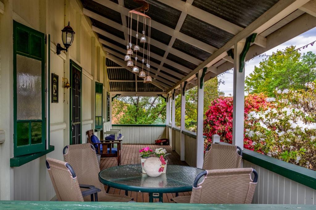 un porche con mesa, sillas y flores en Dillons Cottage en Stanthorpe