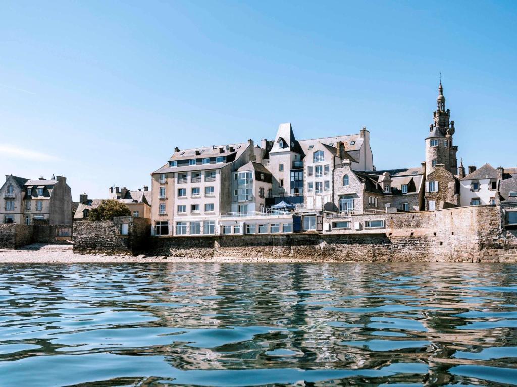 um grande edifício na costa de uma massa de água em Hotel Mercure Roscoff Bord De Mer em Roscoff