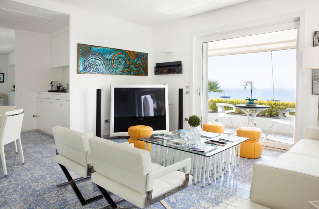カプリにあるLHP Suite Capri Villa La Giaraのリビングルーム(テレビ、テーブル、椅子付)