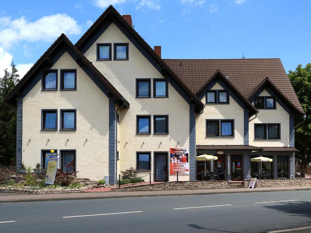 ein großes weißes Haus mit schwarzen Fenstern auf einer Straße in der Unterkunft Hotel Vier Spitzen in Lauenförde