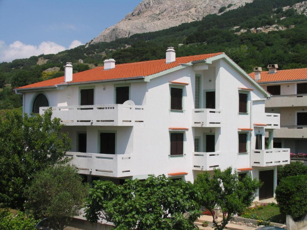 un condominio bianco con una montagna sullo sfondo di Apartments Mohar II a Baška