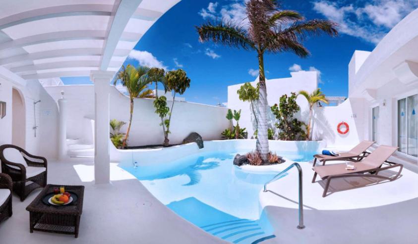 a villa with a swimming pool with a palm tree at Royal Villa Alegria in La Oliva