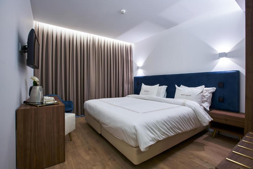 Schlafzimmer mit einem großen Bett mit blauem Kopfteil in der Unterkunft Hotel Moutados in Vila Nova de Famalicão
