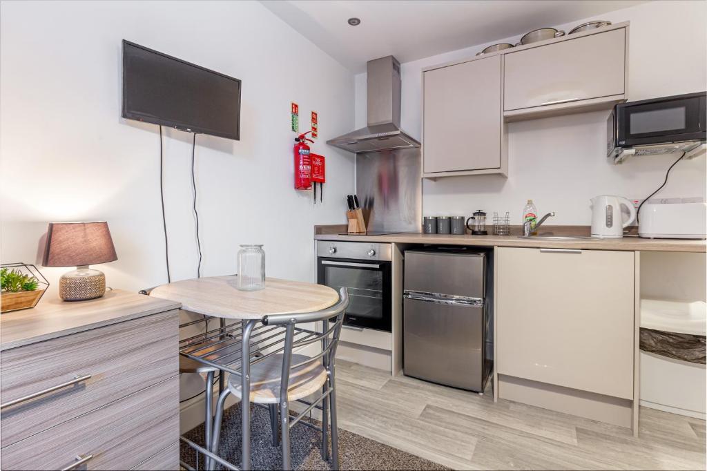 a kitchen with white cabinets and a table and chairs at Guest Homes - The Foregate in Worcester