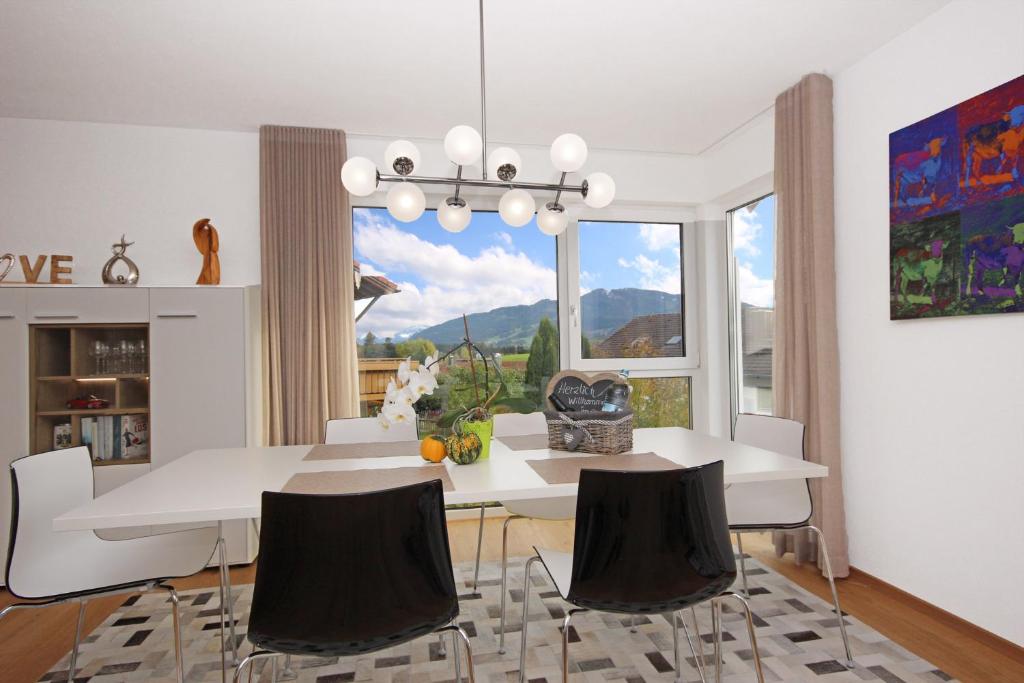 奧伊米特爾貝格的住宿－Alpspitzblick，一间设有白色桌椅和窗户的用餐室