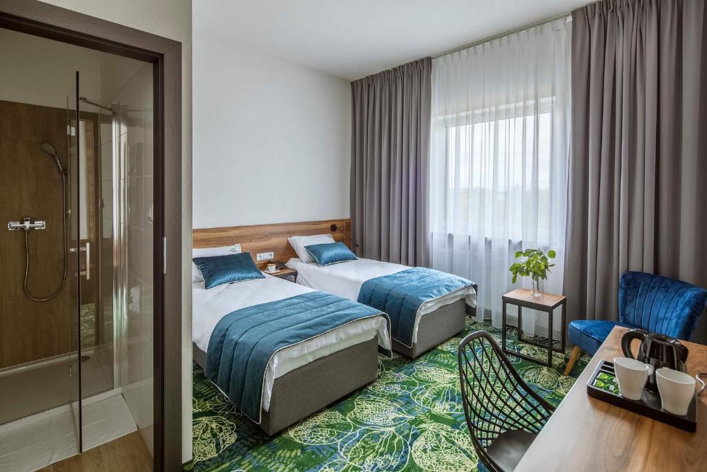 a hotel room with two beds and a shower at Bloom Hotel Airport Okęcie in Raszyn