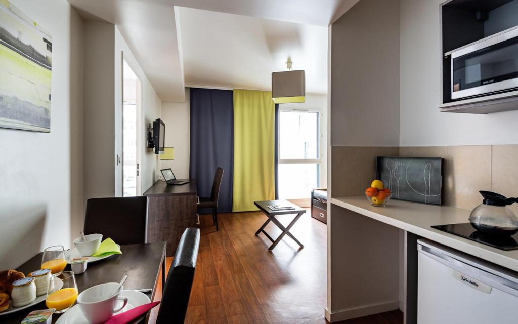 ブローニュ・ビヤンクールにあるLagrange Apart’Hotel Paris-Boulogneのキッチン、リビングルーム(テーブル、椅子付)