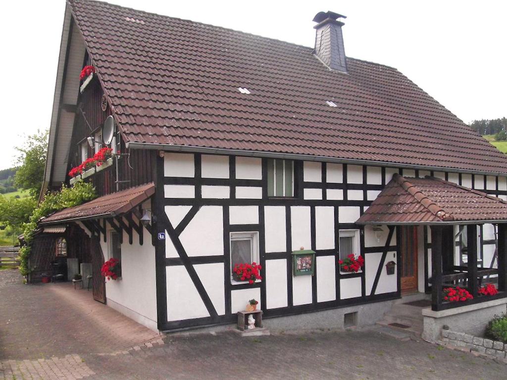 un edificio blanco y negro con flores en las ventanas en Ferienwohnung Hirtenhaus, en Attendorn