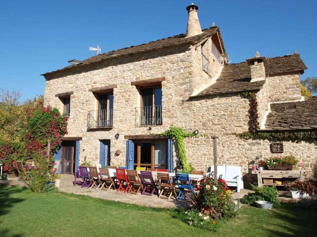 une ancienne maison en pierre avec des chaises et une table dans l'établissement Casapirineos Apartamentos, à Ulle