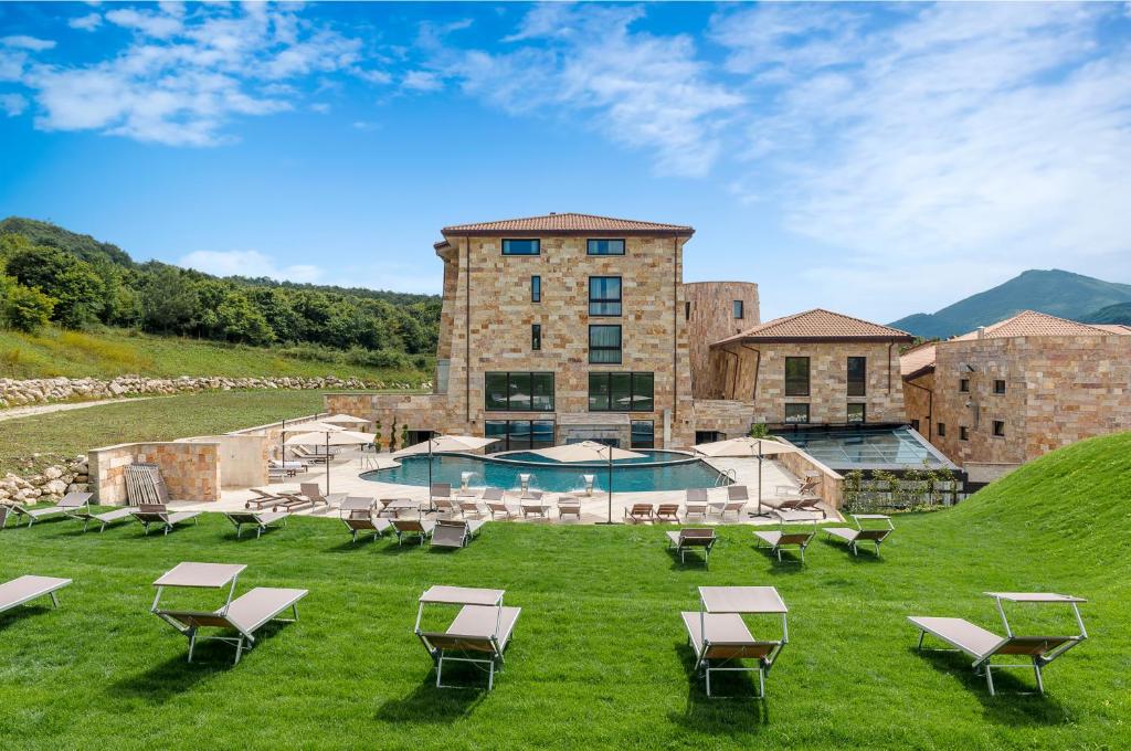 un complexe avec une piscine, des chaises et un bâtiment dans l'établissement Aqua Montis Resort & Spa, à Rivisondoli