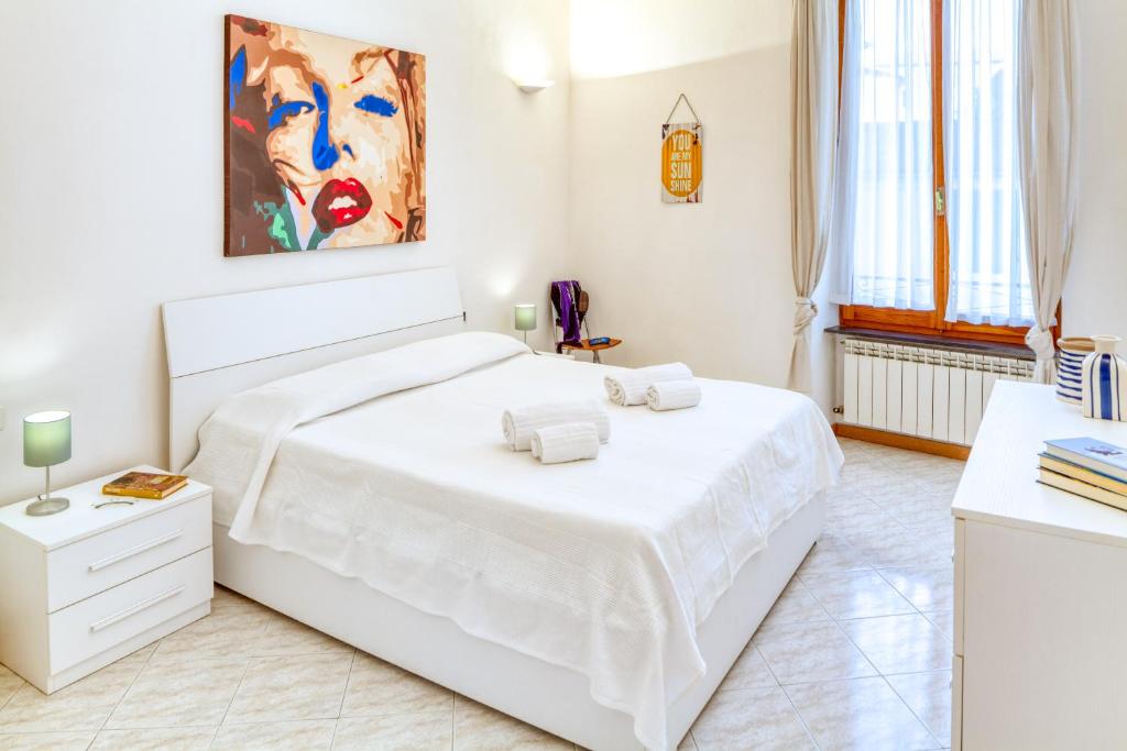 a white bedroom with a white bed and a painting at LUIGINA House in Levanto