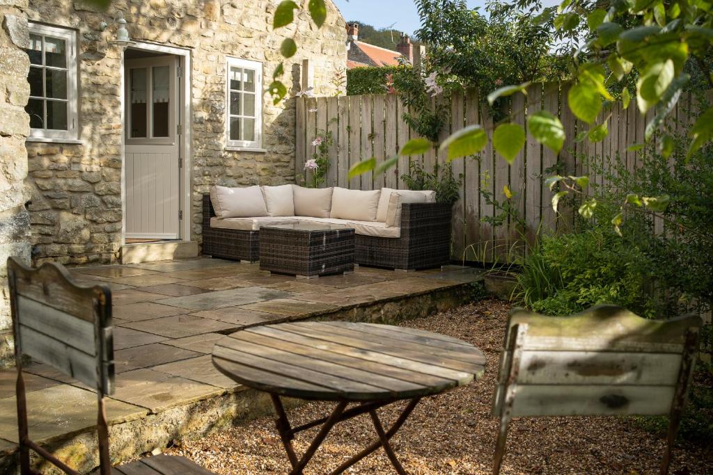 een patio met een bank, stoelen en een hek bij Ford End Cottage in York