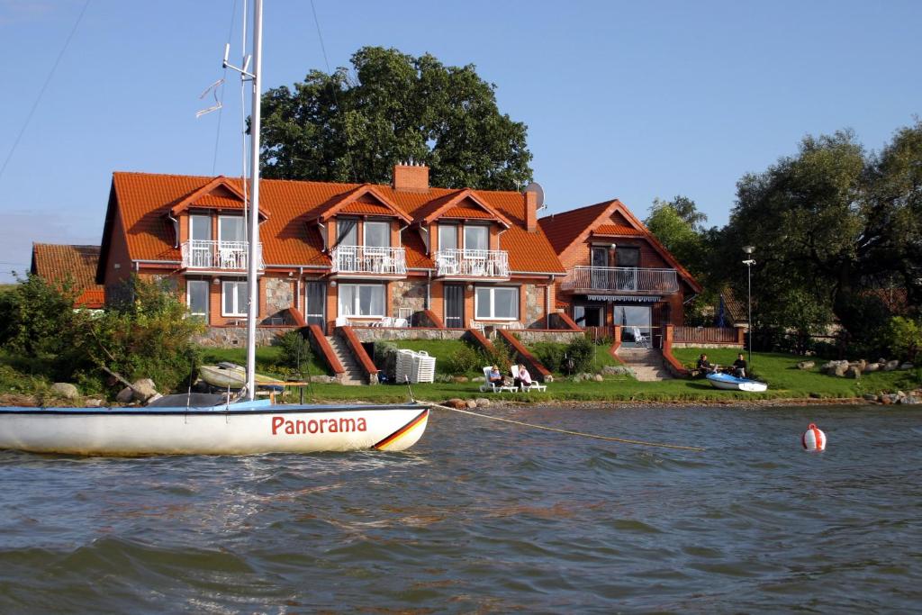 a boat in the water in front of a house at Panorama Lake Resort in Nowe Guty