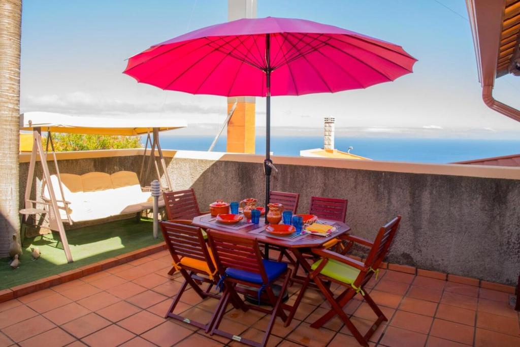 a table with chairs and a red umbrella on a balcony at Charming house in Santa Cruz with sea view in Santa Cruz