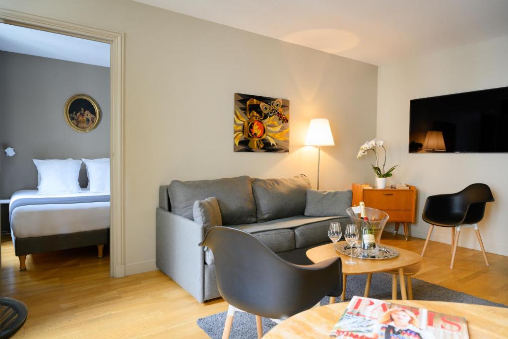 a living room with a couch and a bed at Suites & Hôtel Helzear Champs-Elysées in Paris