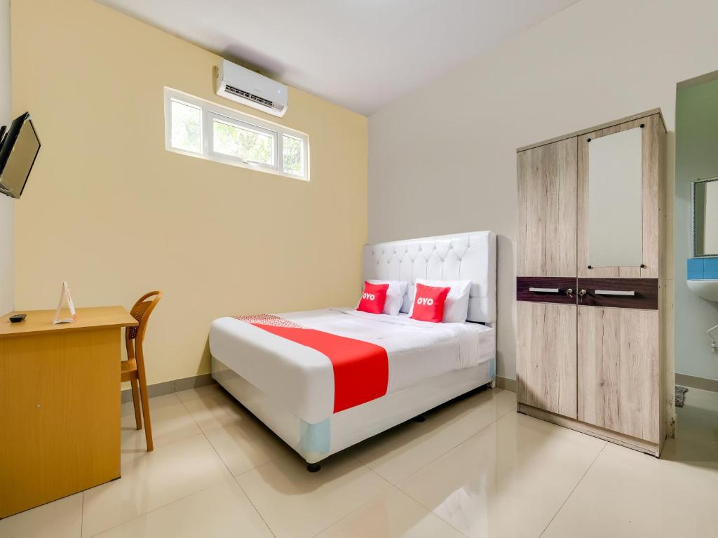 a bedroom with a bed and a desk and a bed at OYO 3972 Simega Residence in Cirebon