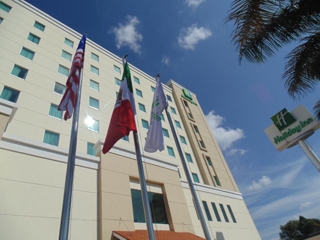 un bâtiment avec drapeaux devant lui dans l'établissement Holiday Inn Uruapan, an IHG Hotel, à Uruapan del Progreso