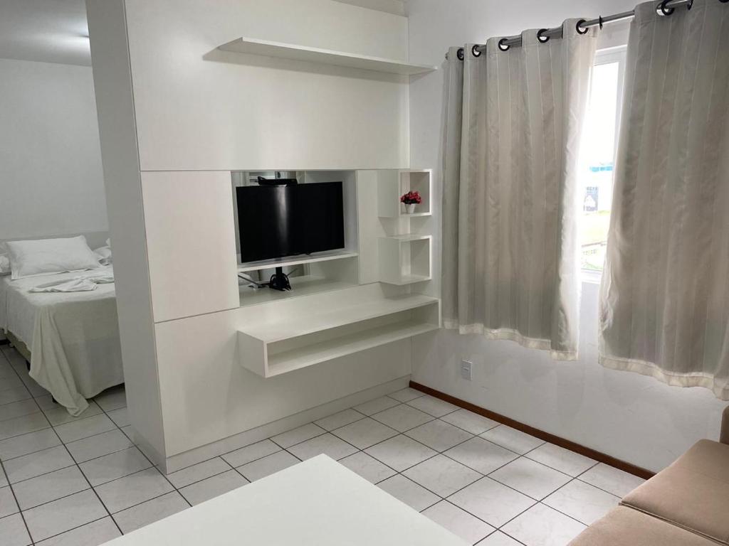 Habitación blanca con TV en la pared en Flat Pedra Branca, en Palhoça