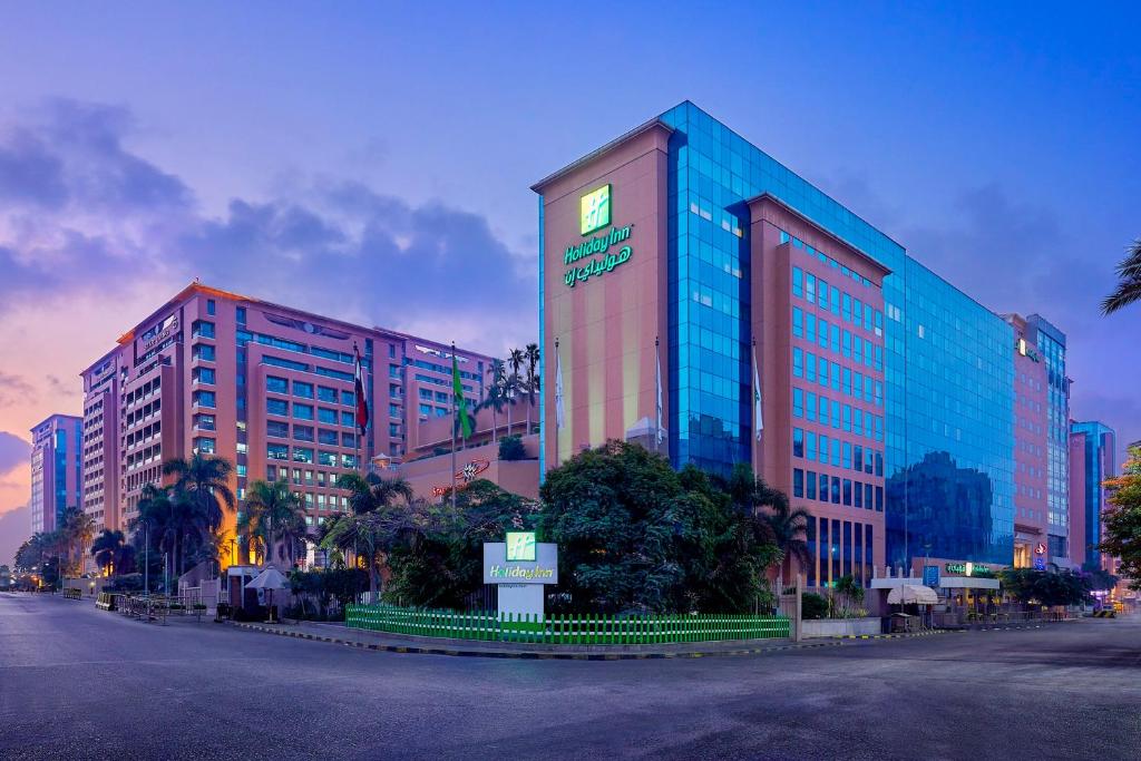 un gran edificio en una calle de la ciudad con palmeras en Holiday Inn Citystars, an IHG Hotel en El Cairo