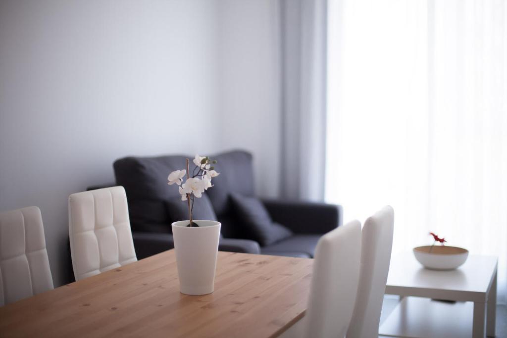 una mesa de comedor con un jarrón con flores. en Sol Playa Suites, en Valencia