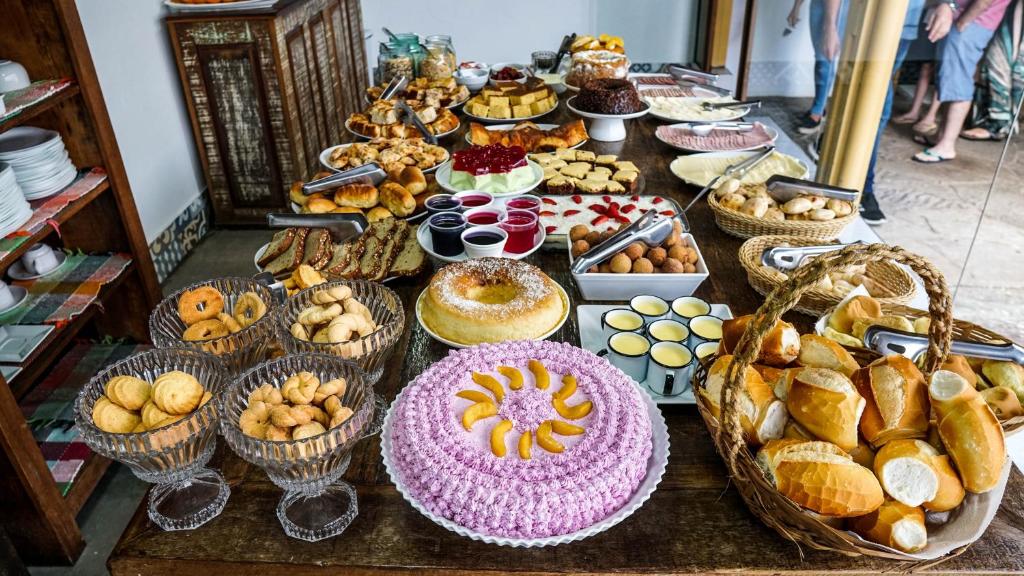 a table filled with different types of pastries and pies at Pousada o Amanhecer in Tiradentes