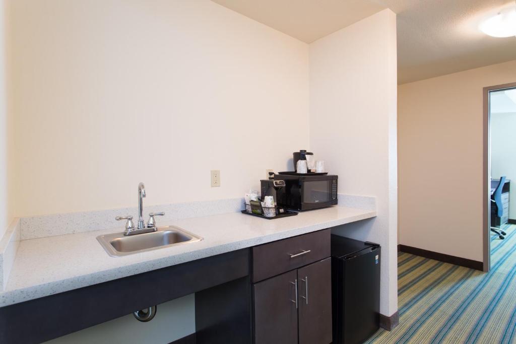 a kitchen with a sink and a microwave at Holiday Inn Texarkana Arkansas Convention Center by IHG in Texarkana