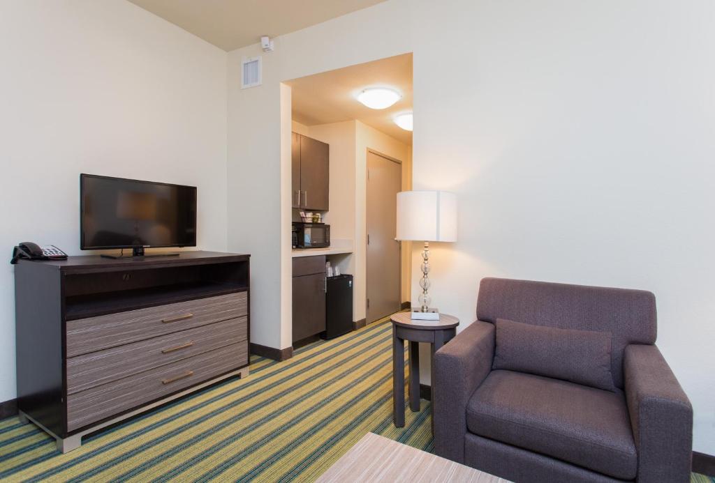 a living room with a chair and a flat screen tv at Holiday Inn Texarkana Arkansas Convention Center by IHG in Texarkana