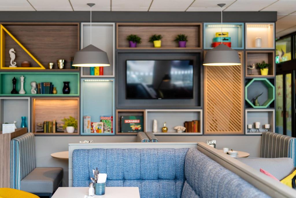a restaurant with a blue couch and a tv at Holiday Inn Bournemouth by IHG in Bournemouth