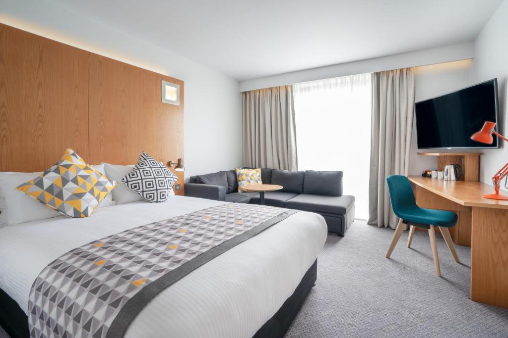 a hotel room with a large bed and a desk at Holiday Inn Bournemouth by IHG in Bournemouth