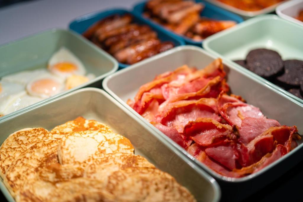 a tray of food with eggs bacon and pancakes at Holiday Inn Bournemouth by IHG in Bournemouth