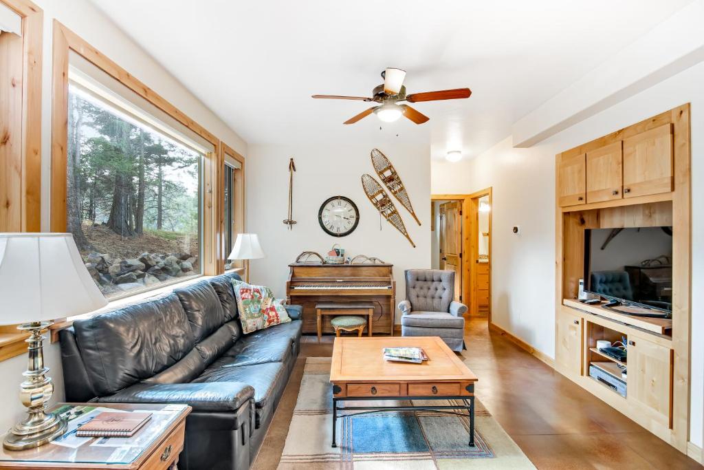 a living room with a leather couch and a piano at Deer Trail in McCall