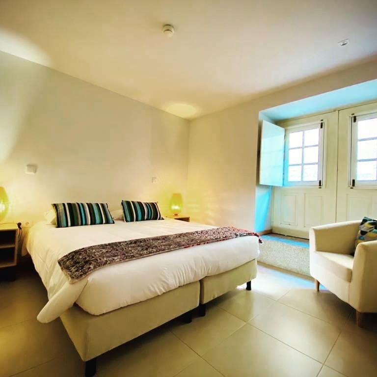 um quarto com uma cama grande e uma cadeira em Aldeia do Tâmega em Amarante