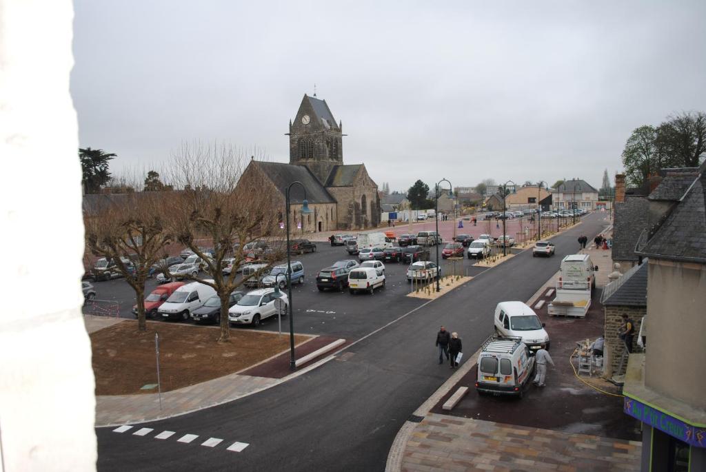a city street with cars parked in a parking lot at Gite Le Jour J in Sainte-Mère-Église