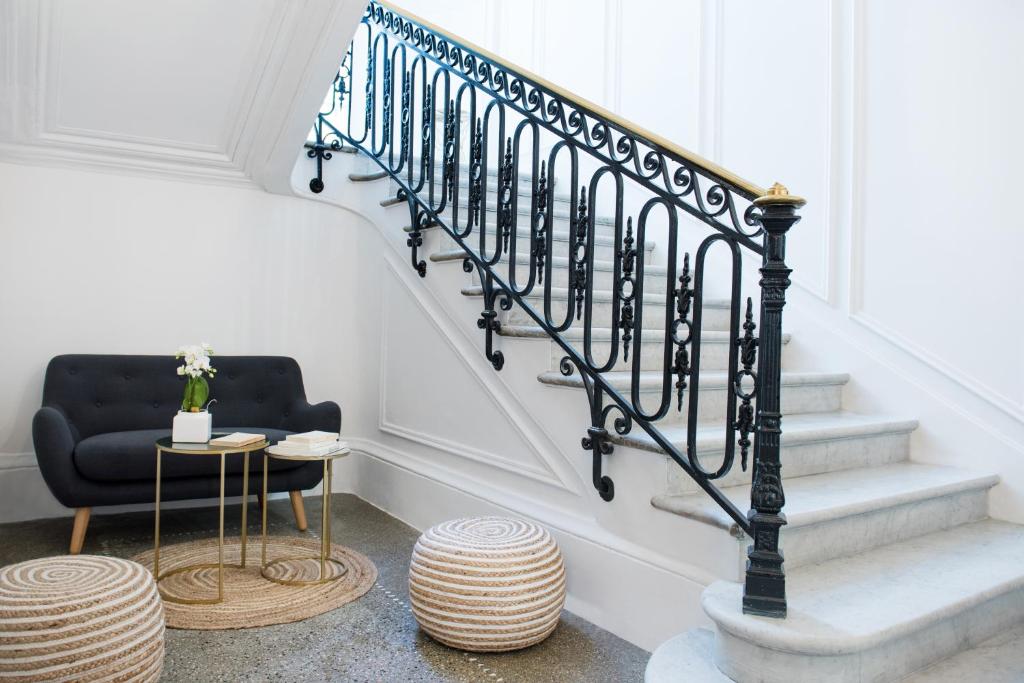 a staircase with a black railing and a chair and a table at Suites & Hôtel Helzear Etoile in Paris